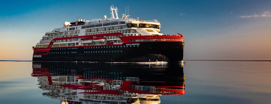 Hurtigruten hybrid cruise ship sailing towards the horizon in calm seas and sunset - Foto:Hurtigruten / Karsten Bidstrup