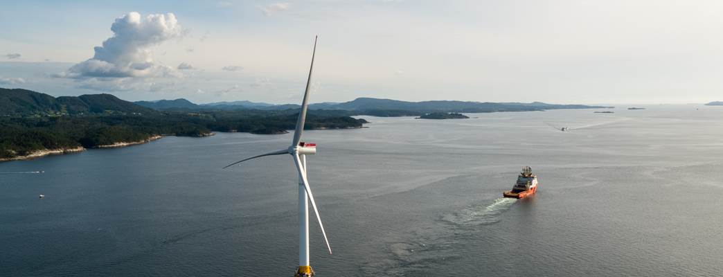 Floating offshore wind turbine in coastal setting with offshore vessel in the distance - Photo:Equinor - Øyvind Gravås