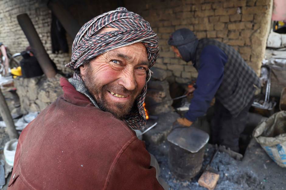 Smiling man with a turban facing the camera while working as a blacksmith