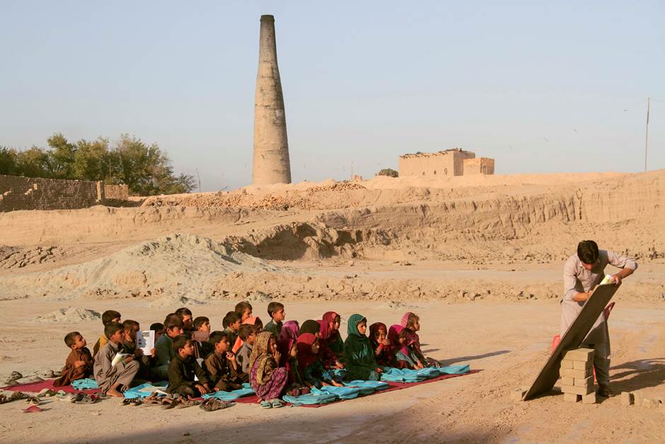 Afghan laborer school children are seen studying in an open space school in a traditional brick fact