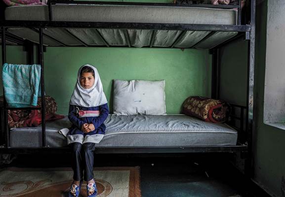 An Afghan girl sitting on her bed at Herat Orphanage Center unwilling to talk, even speak of her nam