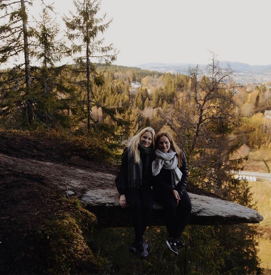 To jenter sitter på en sten i skogen