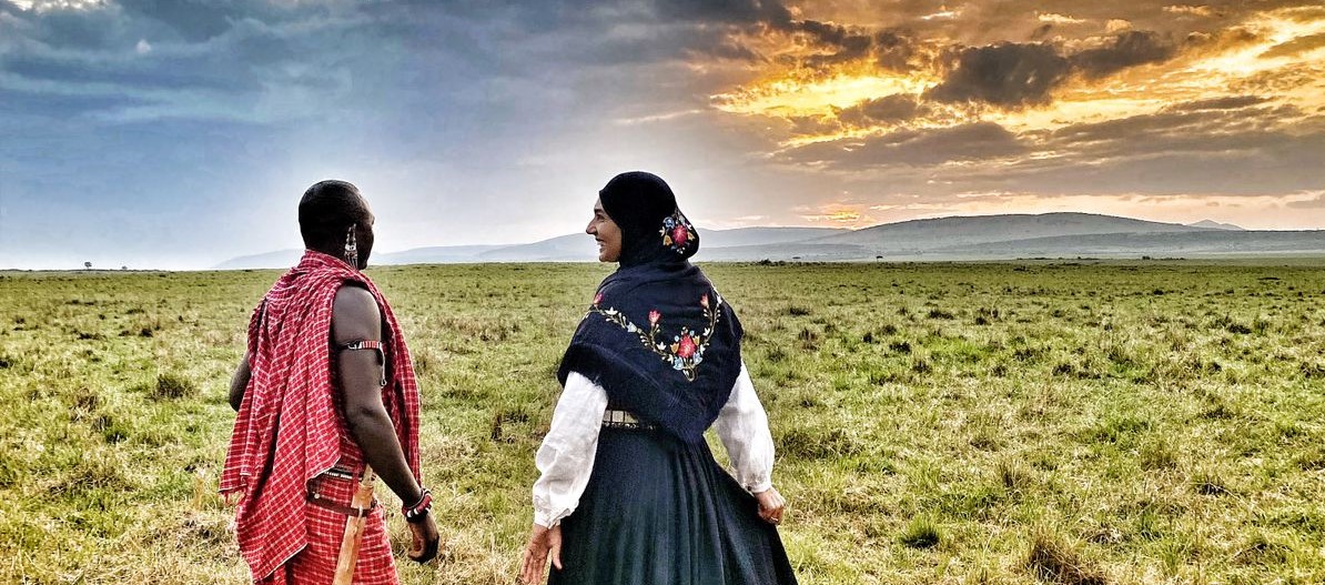 Kenyansk masai og norsk kvinne i bunad i solnedgang. - Foto:Rhine Løvendal