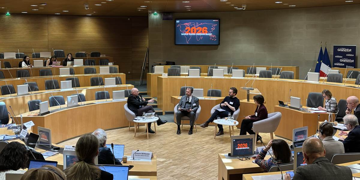Sal med mennesker og skjermer ser mot en paneldiskusjon med fire deltakere