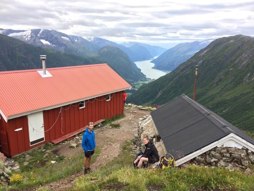 To mennesker foran et gårstun med nydelig fjellutsikt