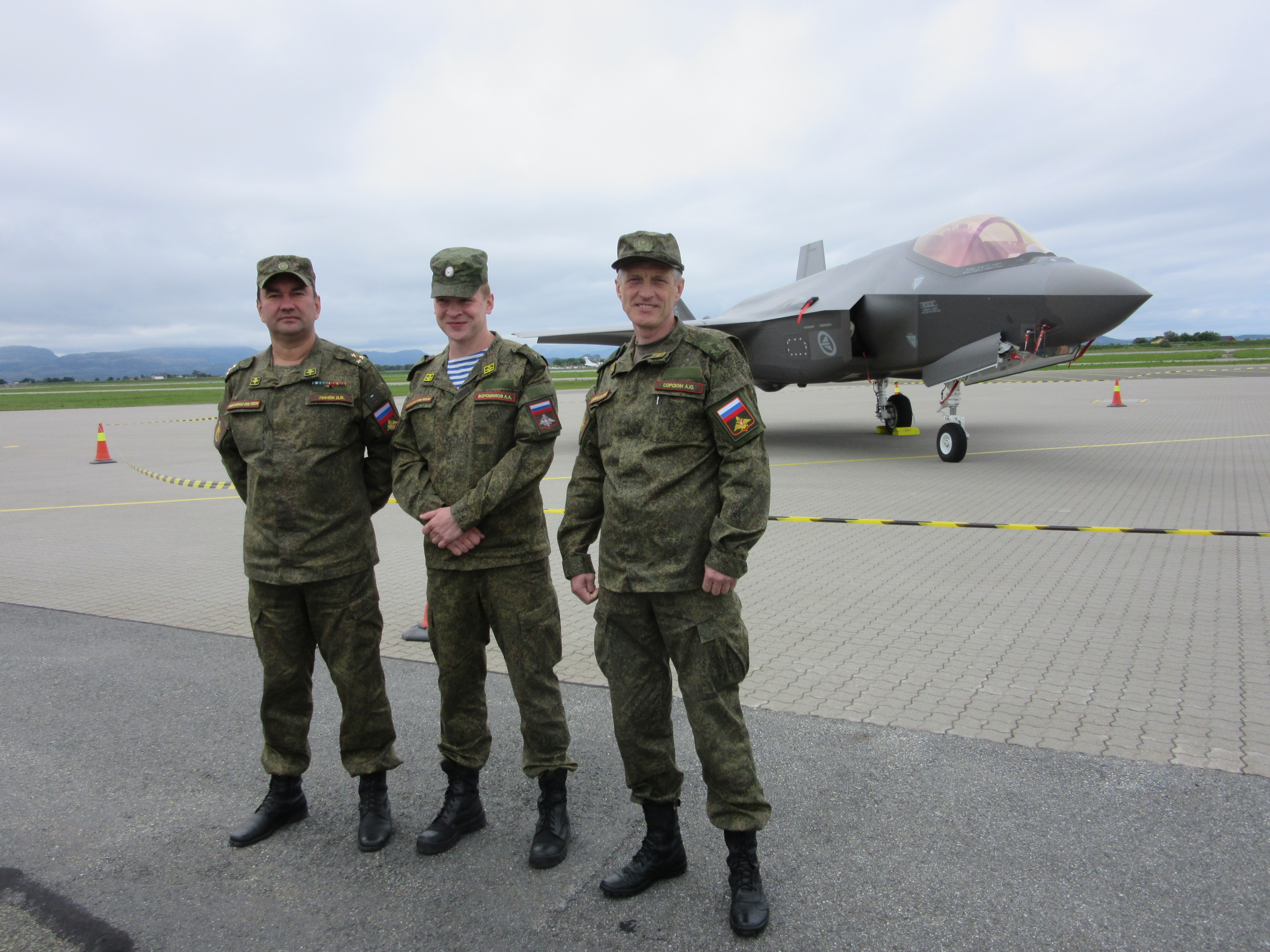 Three Russian officers posing in front of a Norwegian F-35